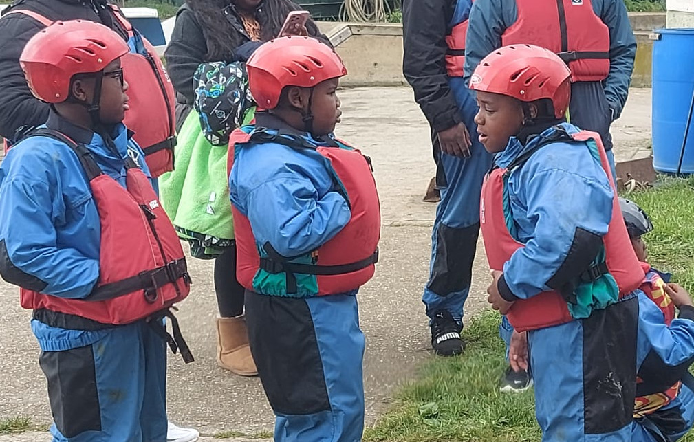 Three children wearing soray jackets, and trousers, boyancy aids and helmets ready to go sailing at EYC