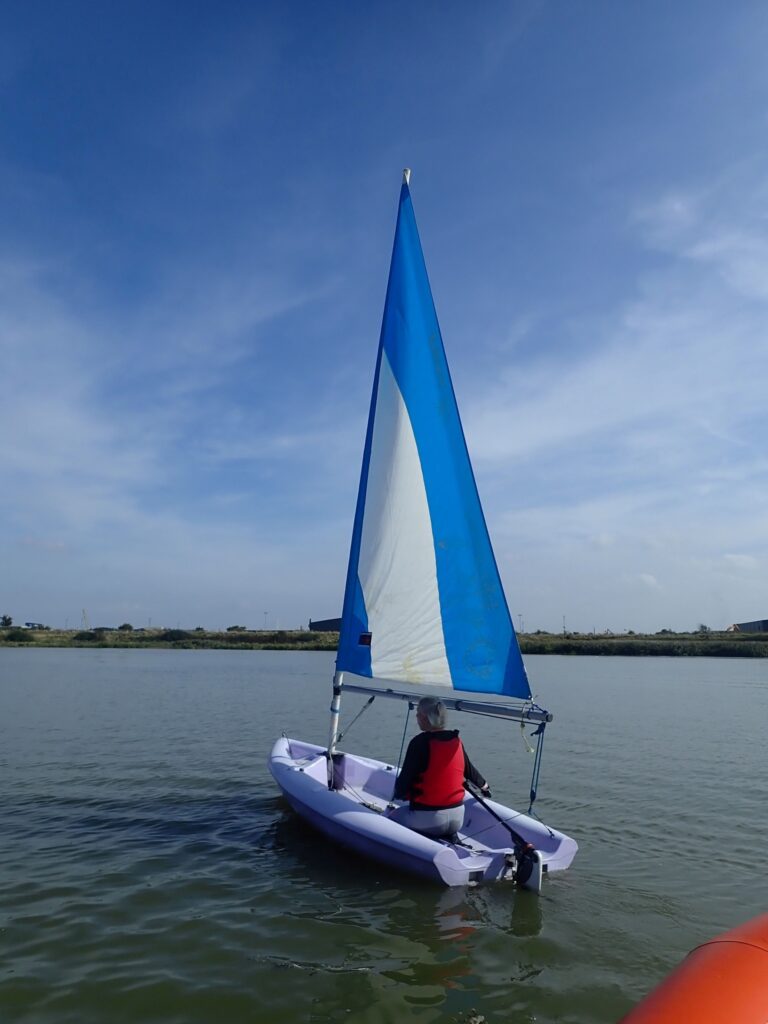 Erith club members sailing a purple Laser Pico in light winds facing away from the camera.